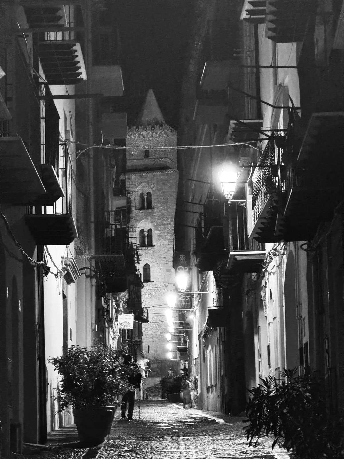 Narrow alley at night with cathedral tower in Cefalù old town