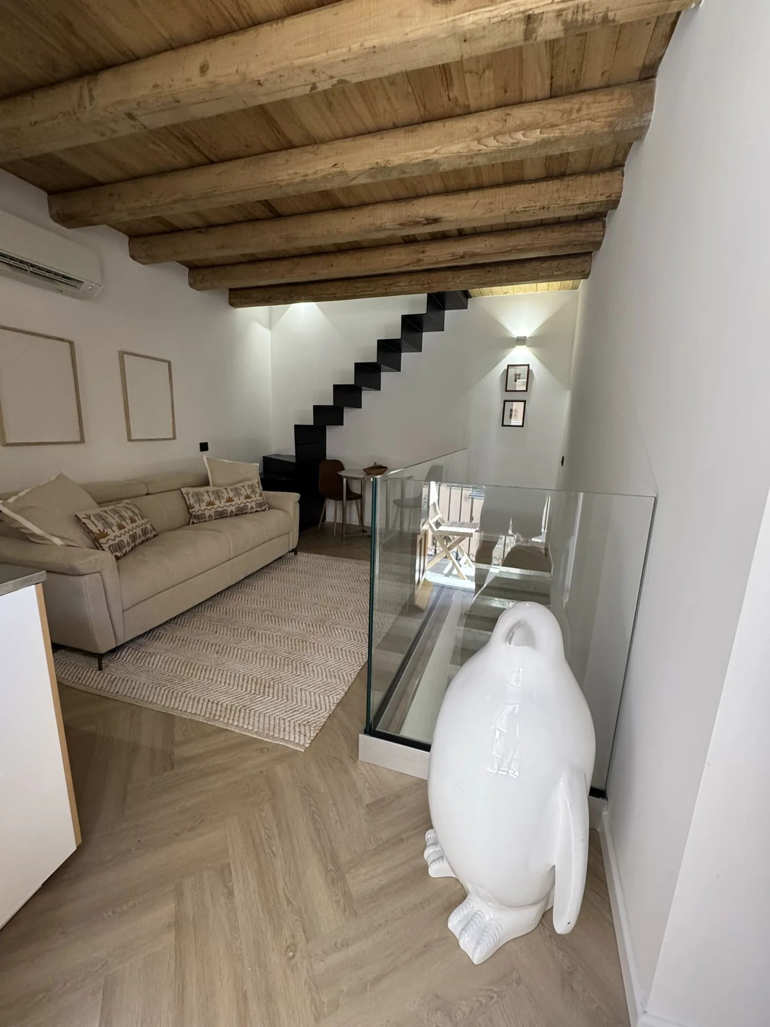 Top-floor living room with sofa, exposed timber beams and a staircase