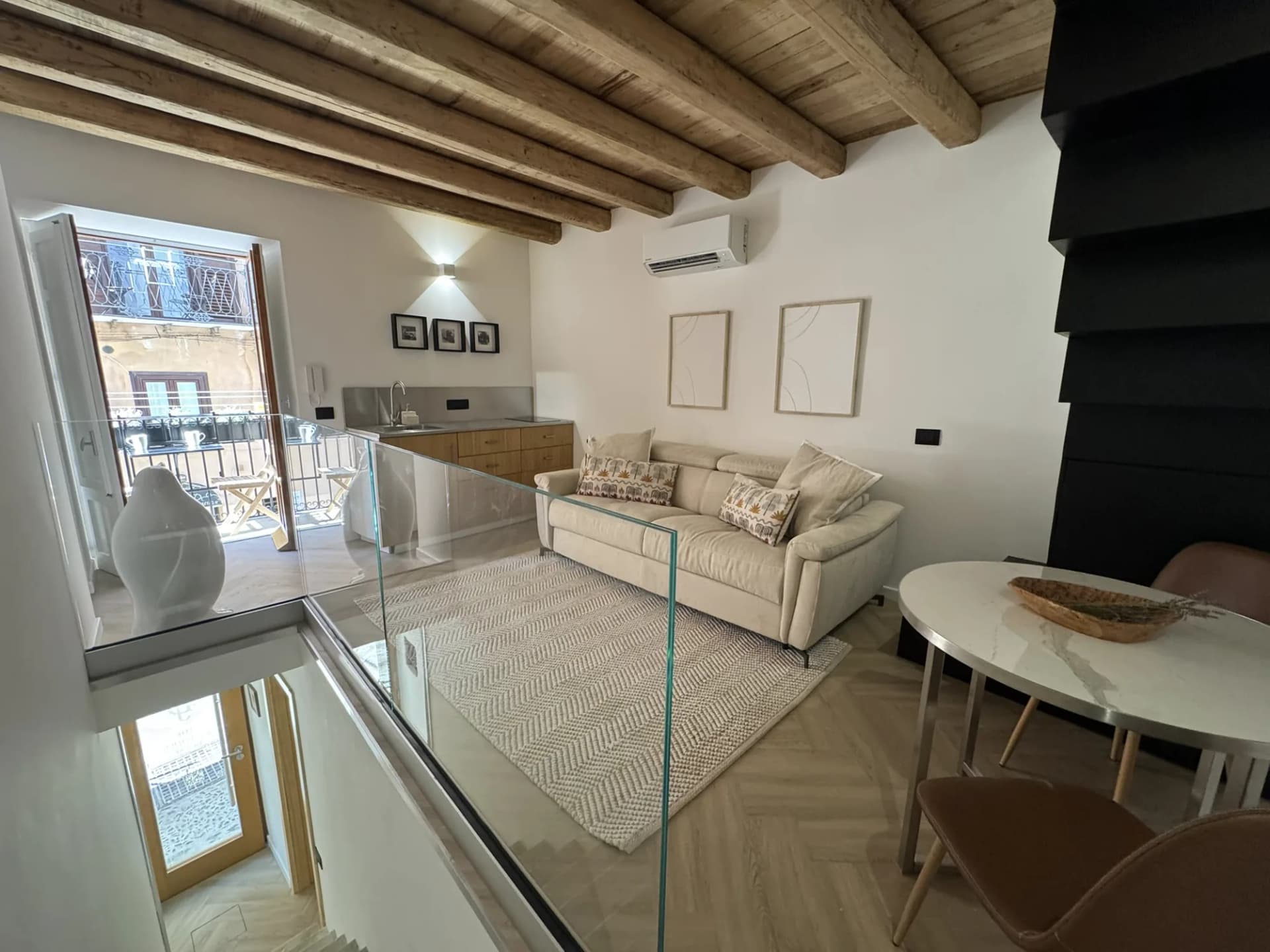 Open living and dining area with a glass balustrade and balcony doors