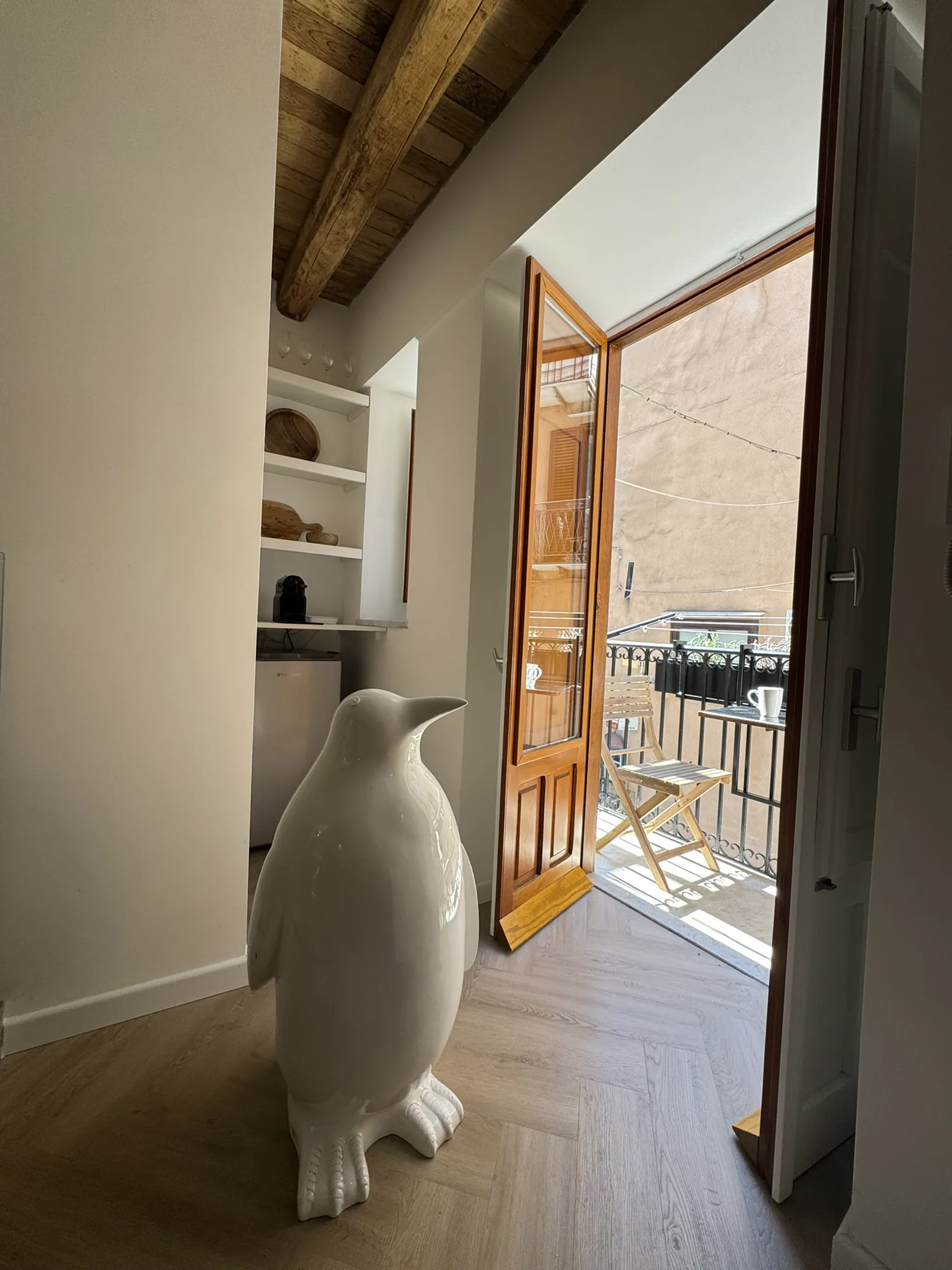 Sitting area with balcony doors thrown open to the rooftops of Cefalù