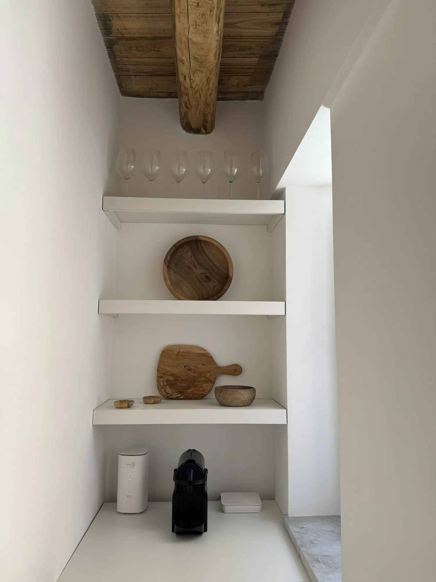 Styled wall niche with wooden bowls and a coffee machine