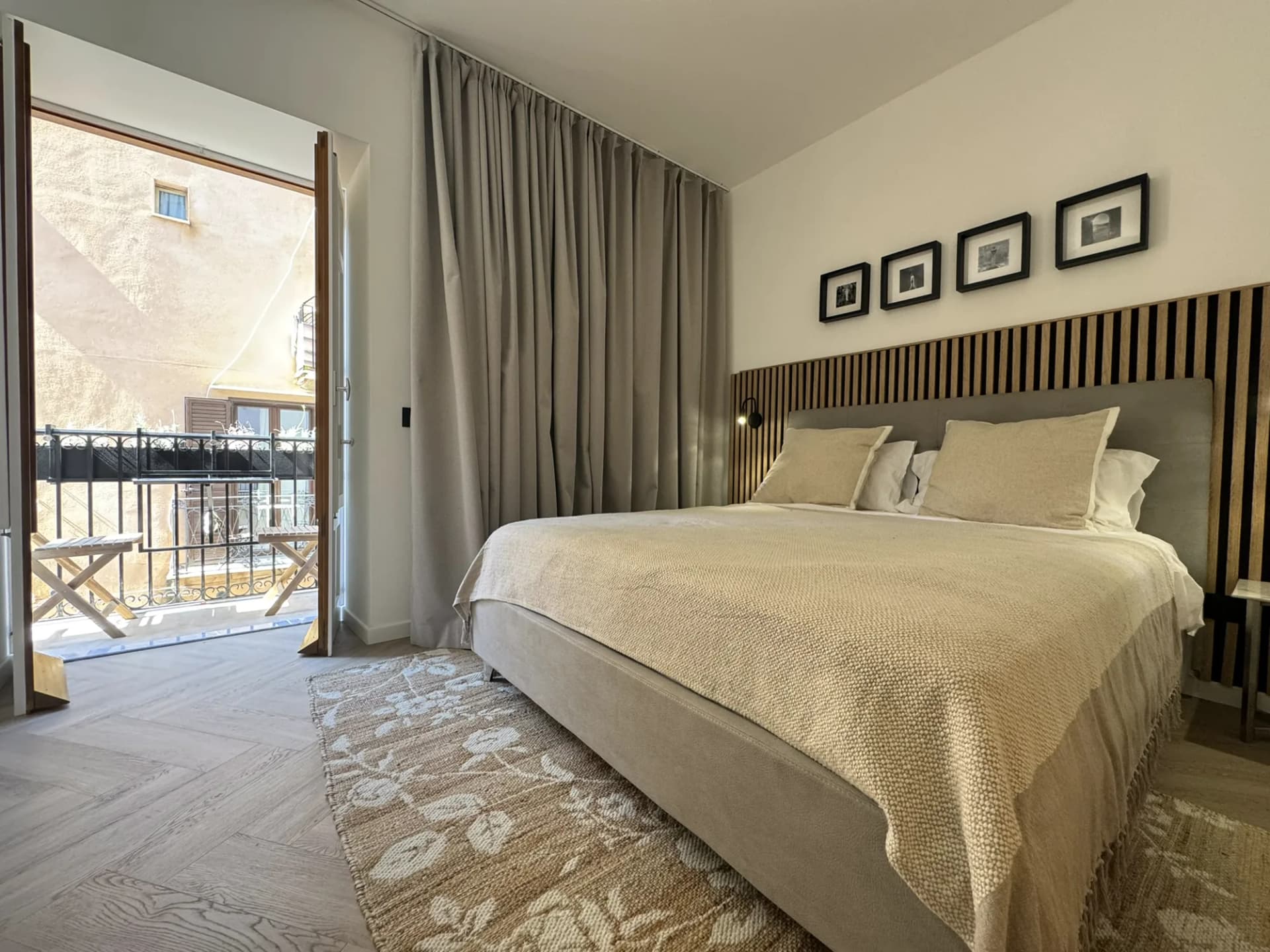 Main double bedroom at The Lavender Townhouse, with a slatted headboard and balcony doors open over the old town