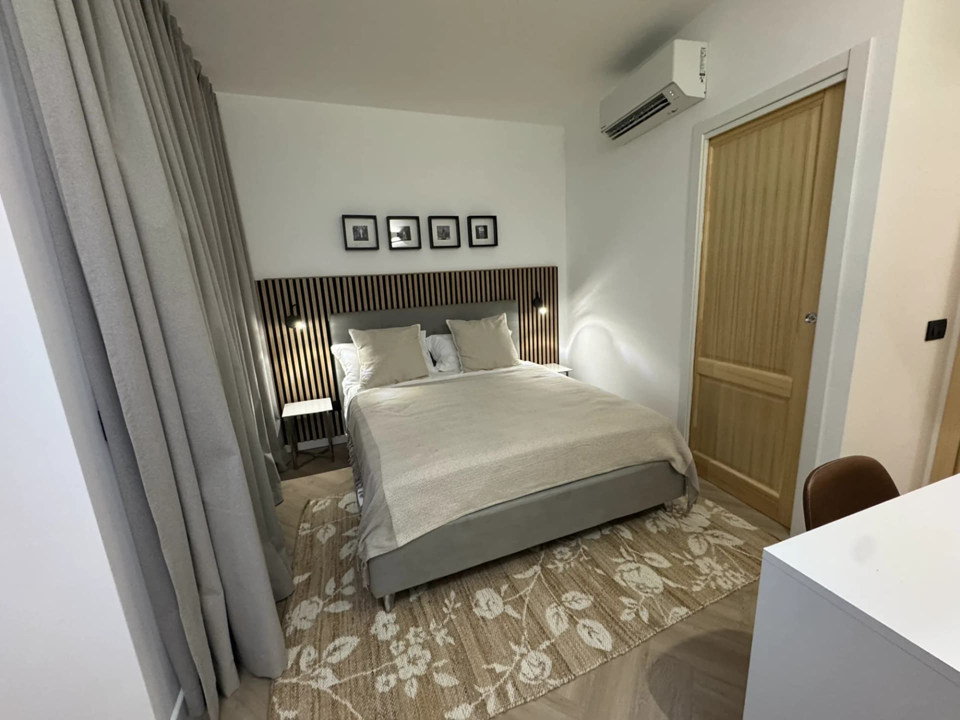 Second double bedroom dressed in soft neutral linens over a herringbone floor