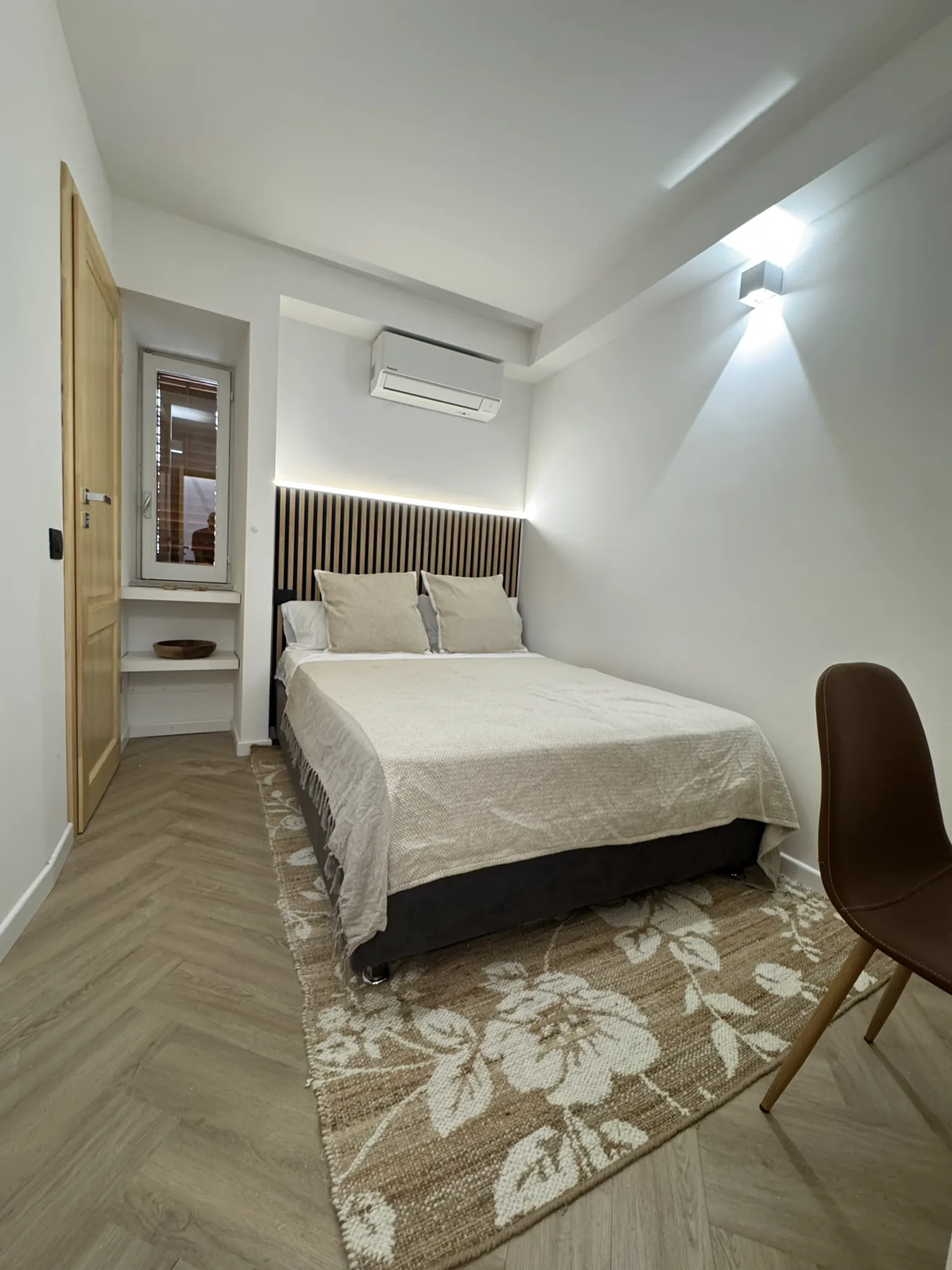 Double bedroom with a patterned rug and a bespoke headboard