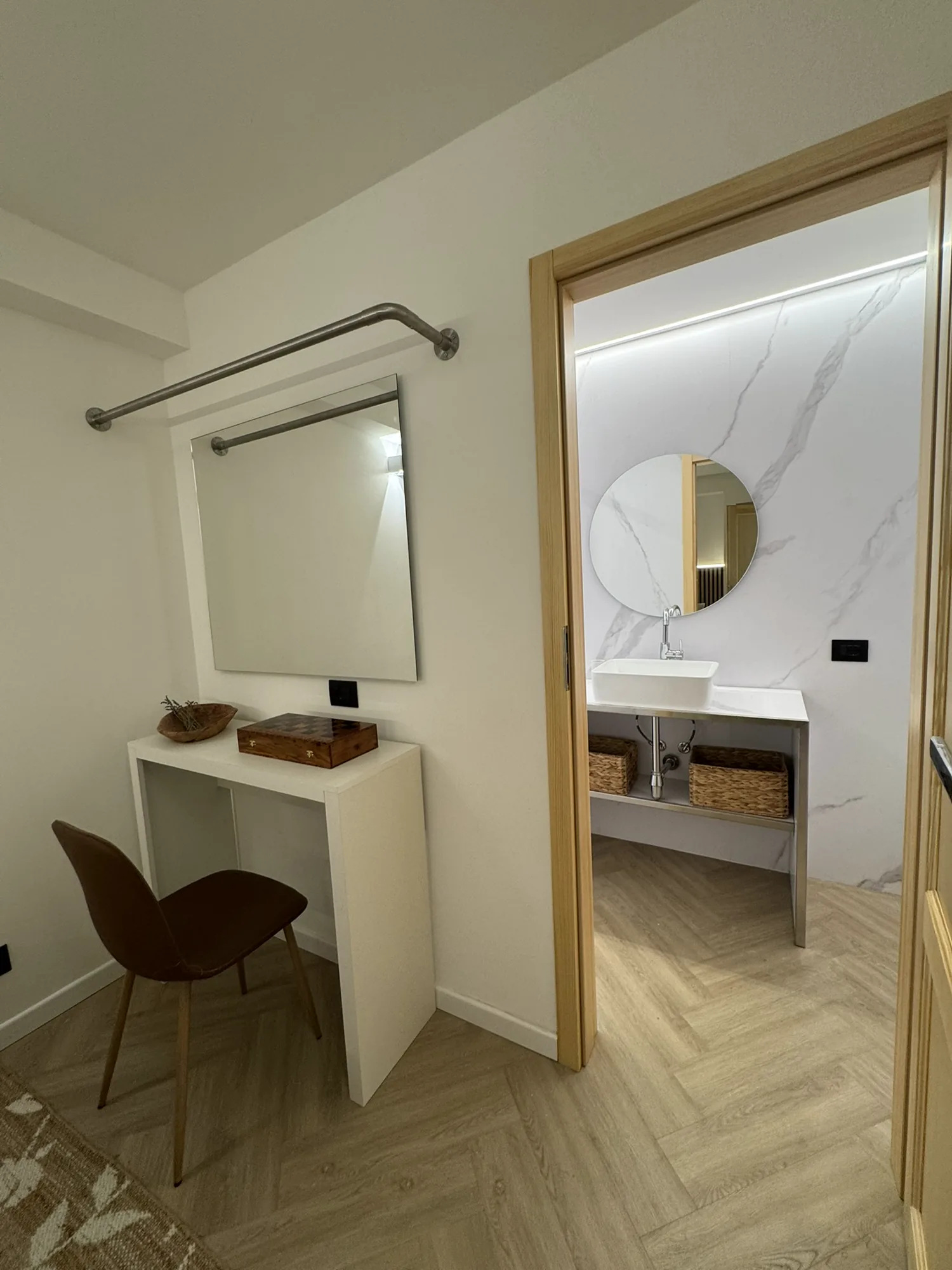 Vanity console with a round mirror beside the marble bathroom
