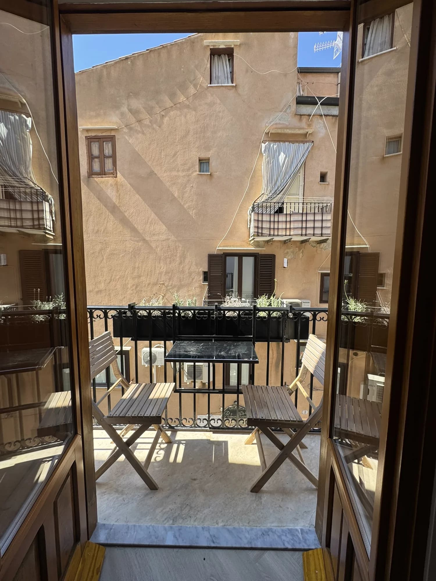 Balcony doors opening onto a bistro table set above Via Candeloro