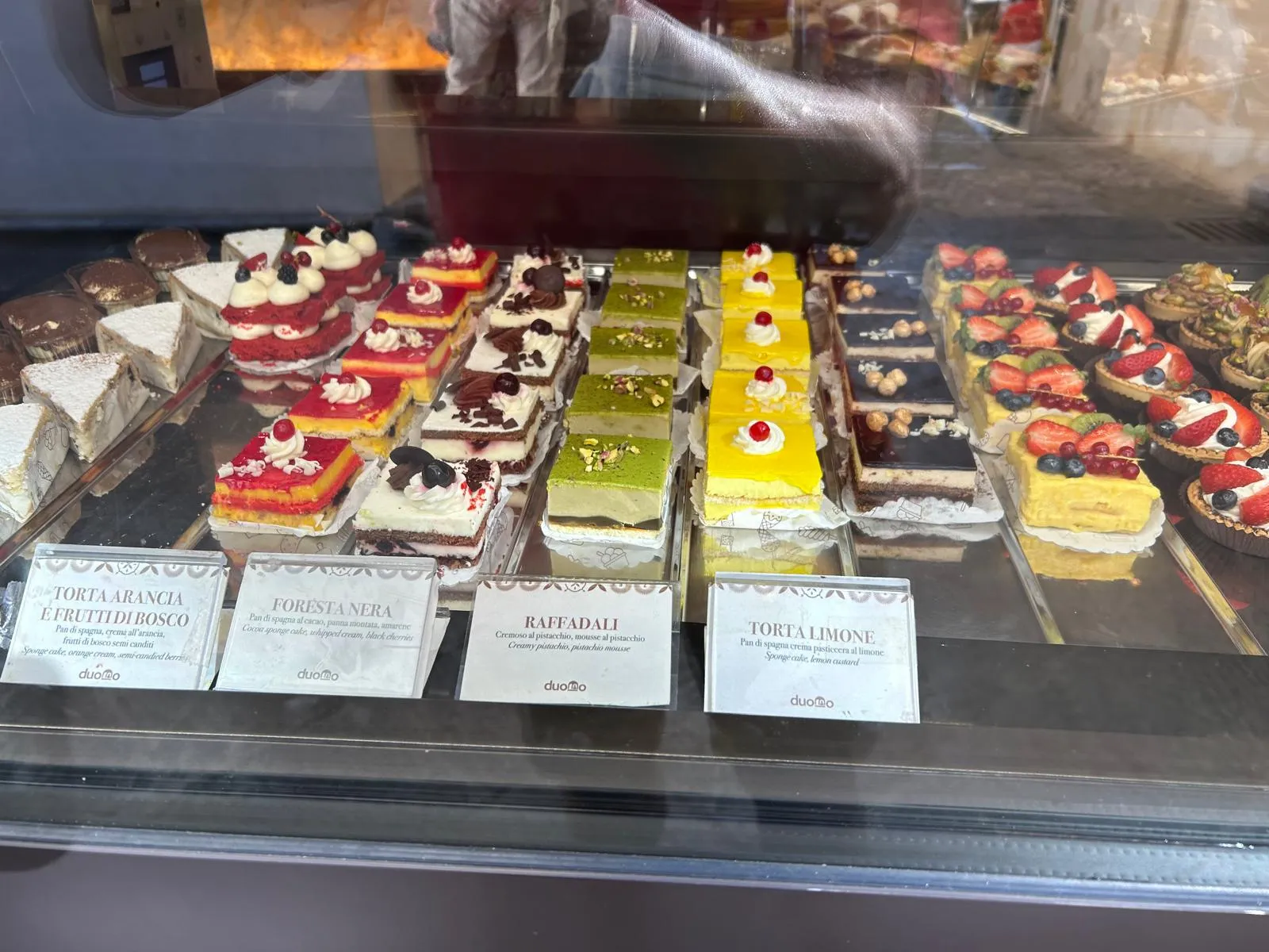 Pastry display case at a Cefalù pasticceria — cornetti, pistachio cakes, and fruit tarts