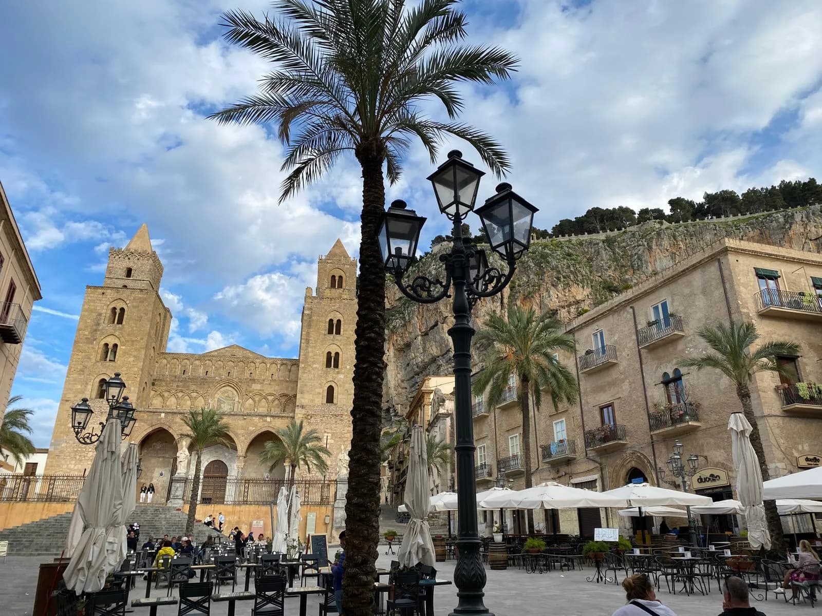Piazza del Duomo with the cathedral towers, palm trees, and La Rocca behind