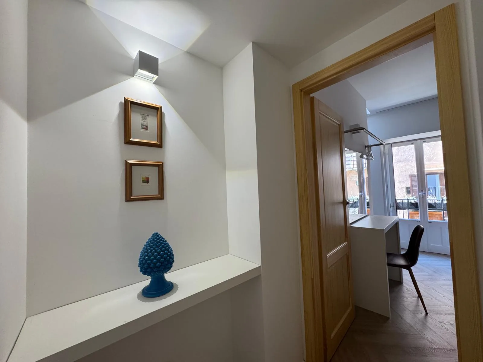 The landing at The Lavender Townhouse — a blue ceramic pigna on a shelf beside the doorway to the bedroom