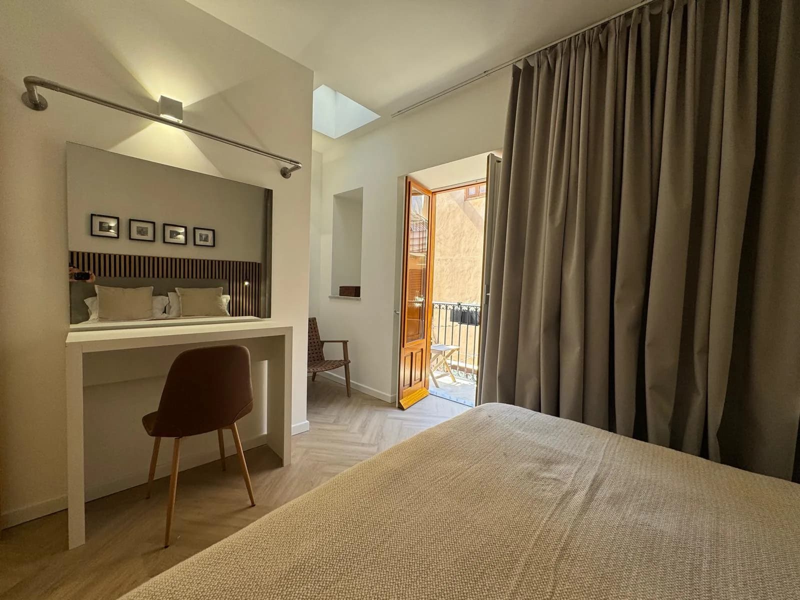 A bedroom at The Lavender Townhouse — bed with a slatted headboard and reading light, opening onto a balcony
