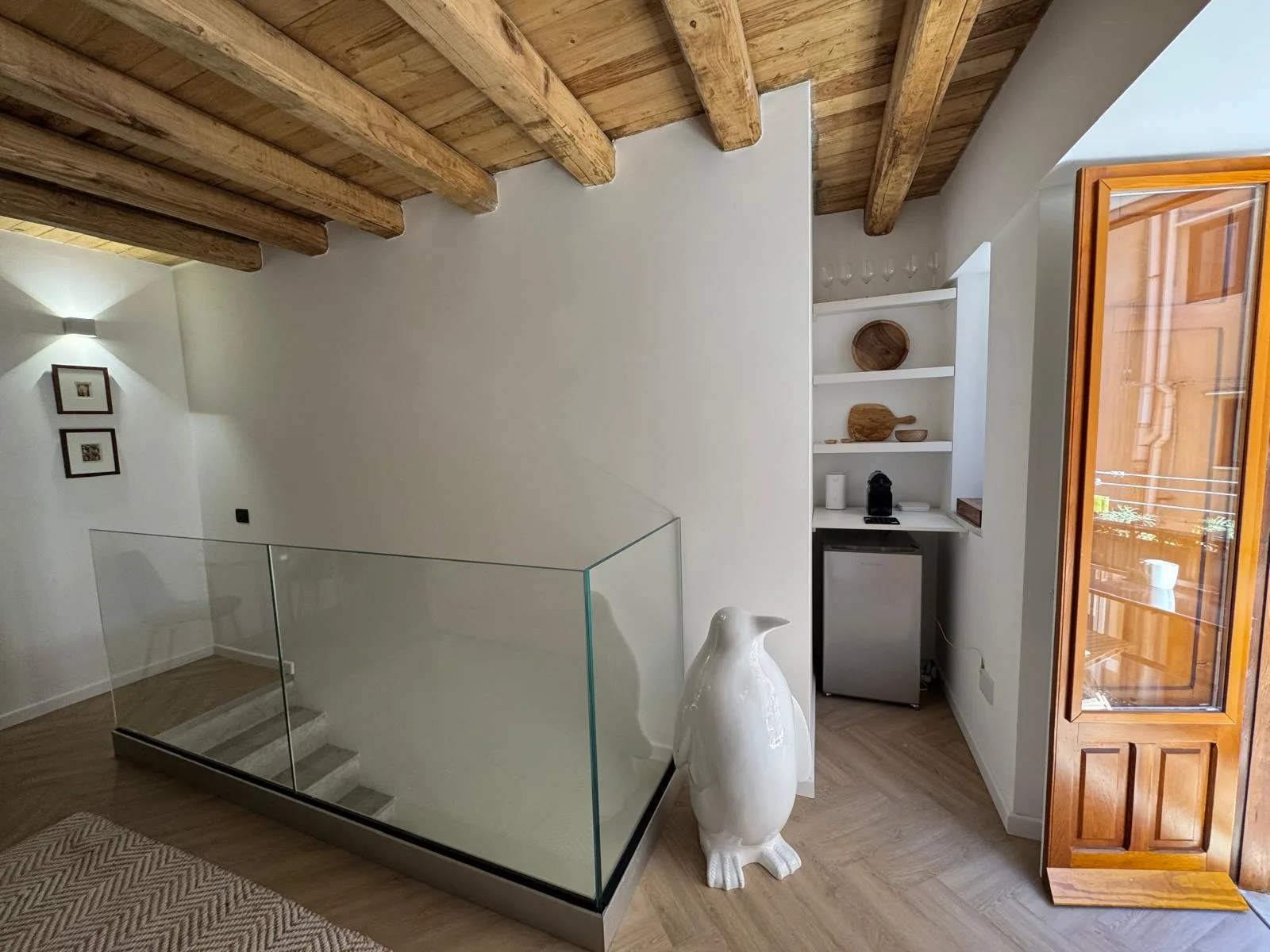 The landing at The Lavender Townhouse — a glass balustrade over the stair and a coffee niche beneath the beamed ceiling