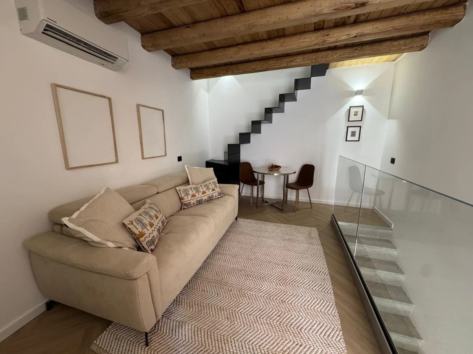 The living room at The Lavender Townhouse — sofa and dining table beside a black staircase rising to the mezzanine